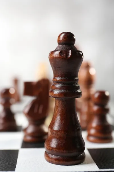 Placa de xadrez com peças de xadrez em fundo cinza — Fotografia de Stock