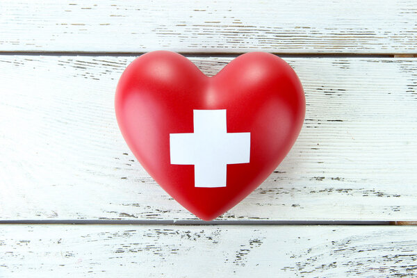 Red heart with cross sign on color wooden background