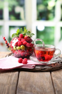 Yabani çilek cam bardakta parlak zemin üzerine ahşap masa ile kırmızı meyve çayı