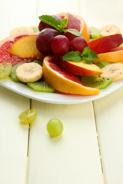Beyaz ahşap masa üzerinde plaka üzerinde dilimlenmiş meyve çeşitleri — Stok fotoğraf