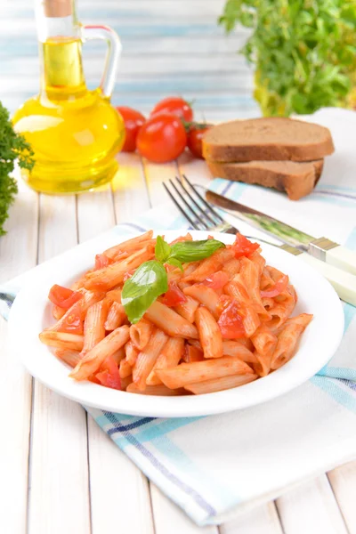 Pasta med tomatsås på tallriken på bordet på ljus bakgrund — Stockfoto