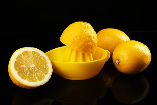 Citrus squeezer with lemons on black background — Stock Photo, Image