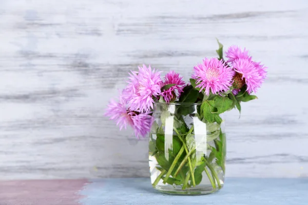 Cornflowers in glass jar on wooden background — Stock Photo, Image