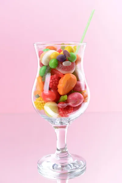 Different colorful fruit candy in glass on pink background — Stock Photo, Image