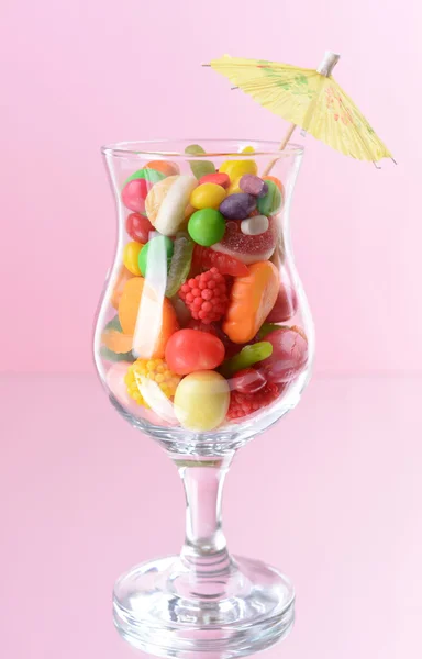 Verschillende kleurrijke fruit snoep in glas op roze achtergrond — Stockfoto