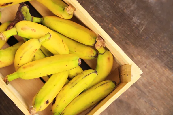 Ramo de mini plátanos en caja de madera sobre fondo de madera —  Fotos de Stock