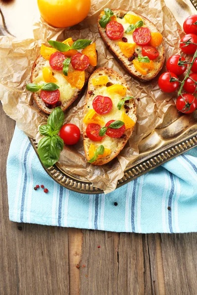 Tasty bruschetta with tomatoes, on old wooden table — Stock Photo, Image