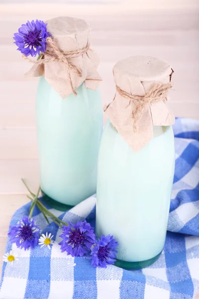 Garrafas com leite e flores de milho na mesa de madeira — Fotografia de Stock