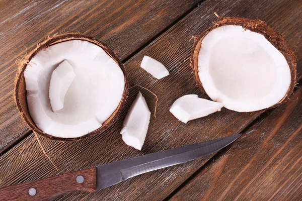 Trasiga kokos med kniv på trä bakgrund — Stockfoto