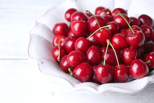 Sweet cherries in color bowl on wooden background — Stock Photo, Image