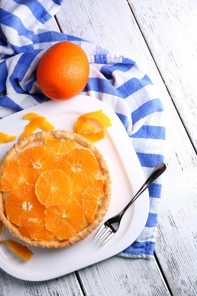 Crostata all'arancia fatta in casa su piatto, su sfondo di legno a colori — Foto Stock