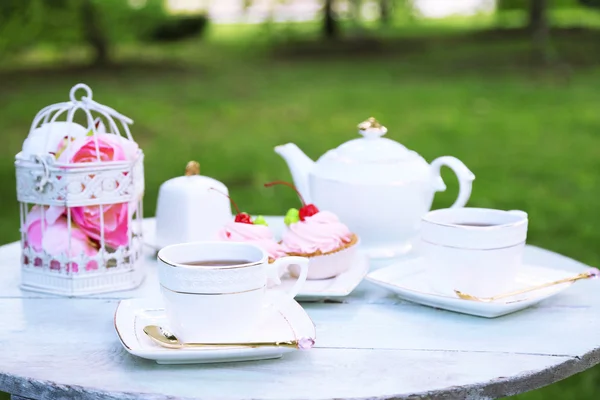 Soffbord med tekoppar och välsmakande kakor i trädgården — Stockfoto