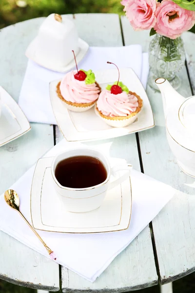 Mesa de café com xícaras de chá e bolos saborosos no jardim — Fotografia de Stock