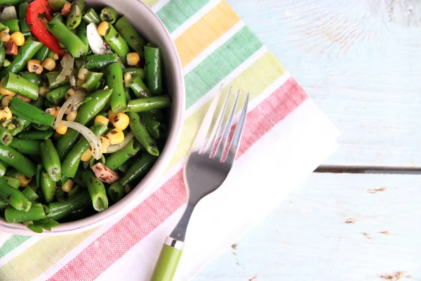 Salade met ham, groene bonen en maïs in kom, op een houten achtergrond kleur — Stockfoto