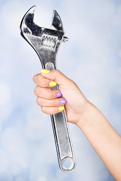 Mão feminina com unhas coloridas elegantes segurando chave, no fundo de cor — Fotografia de Stock