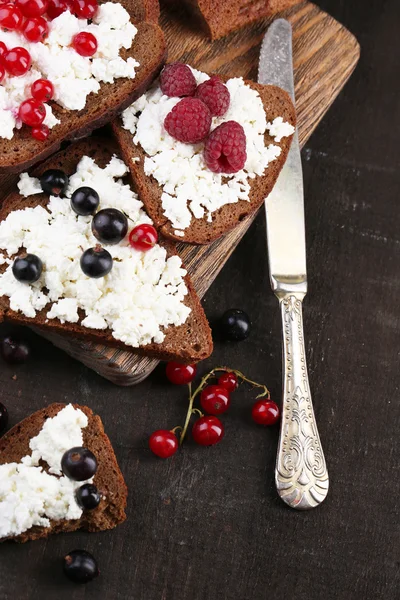 Bread with cottage cheese and berries on wooden board close-up — Stock Photo, Image