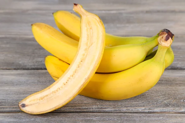 Halved and whole ripe bananas on wooden background — Stock Photo, Image