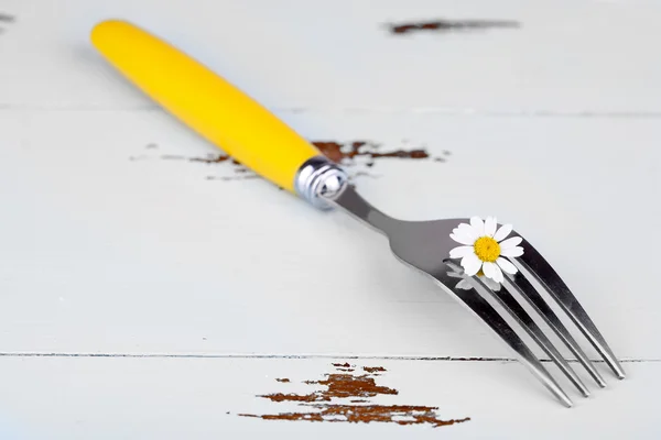 Fork with daisy flower, on wooden background — Stock Photo, Image