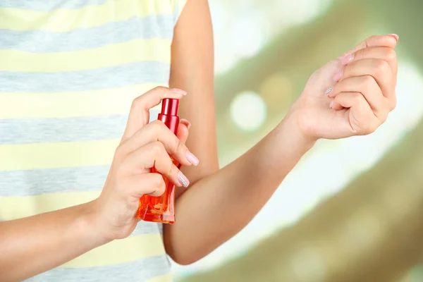 Frau testet Parfüm auf hellem Hintergrund — Stockfoto