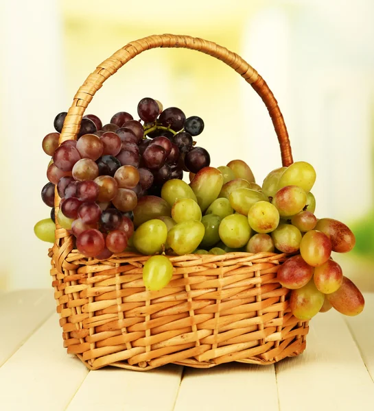 Fresh grape on wicker mat on bright background — Stock Photo, Image