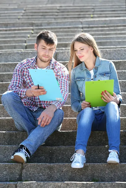 Счастливые студенты сидят на лестнице в парке — стоковое фото