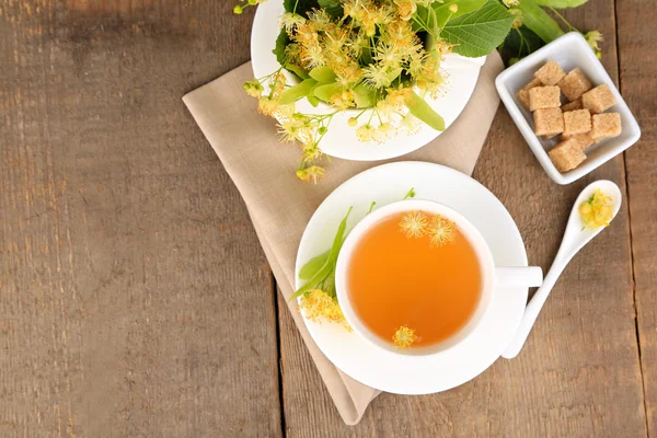 Tasty herbal tea with linden flowers on wooden table — Stock Photo, Image