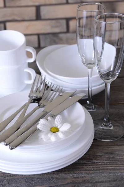 Set weißer Gerichte auf dem Tisch auf Ziegelwand-Hintergrund — Stockfoto