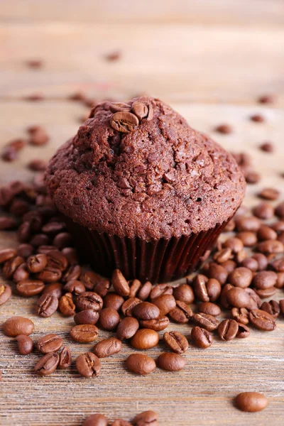 Čokoládový muffin a kávové zrna na dřevěné pozadí — Stock fotografie