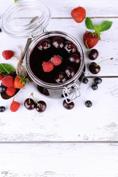 Leckere Marmelade mit Beeren im Glas auf Holztisch — Stockfoto