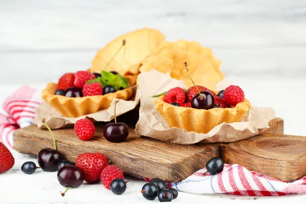 Tasty tartlets with berries on wooden table — Stock Photo, Image