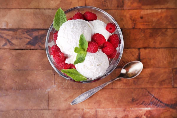 Romige ice cream met frambozen op plaat in glazen kom, op een houten achtergrond kleur — Stockfoto