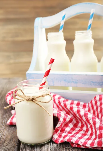 Milch in Flaschen mit Papierhalmen auf dem Tisch — Stockfoto