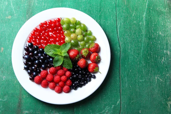 Forest berries on plate, on color wooden background — Stock Photo, Image