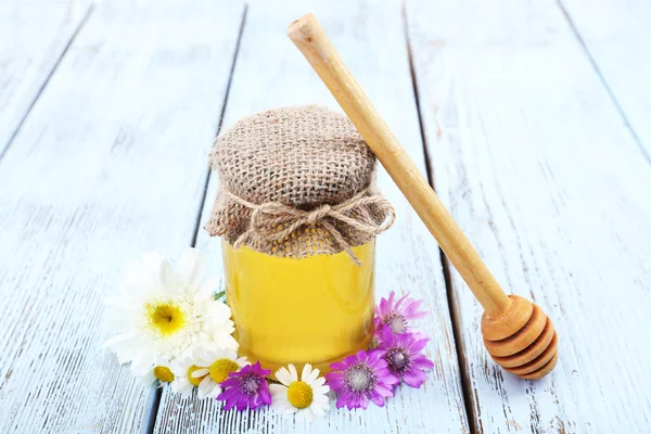 Glas voll leckerem frischen Honig und Wildblumen auf Holztisch — Stockfoto