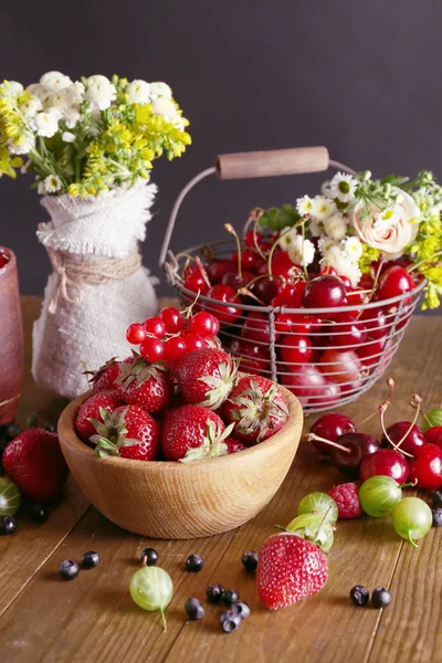 Stilleven met bessen en bloemen op houten tafel close-up — Stockfoto