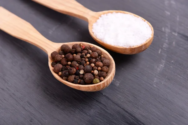 Salt and pepper in spoon on wooden table close-up — Stock Photo, Image