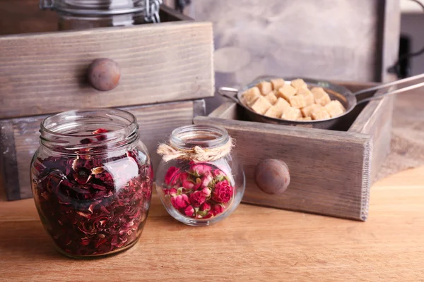 Dried hibiscus tea in glass jar, brown sugar  in box on wooden background — Stock Photo, Image