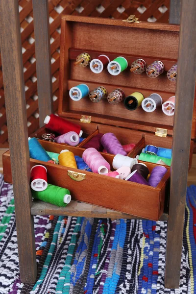 Colorful threads for needlework in wooden box on shelf in room — Stock Photo, Image