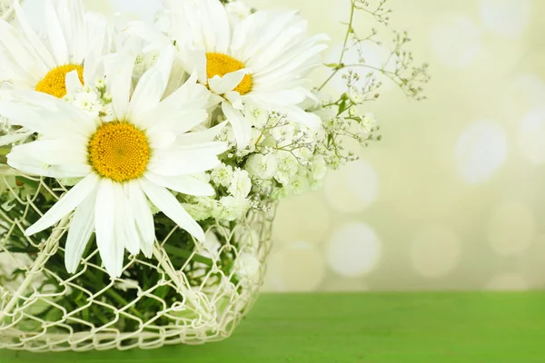 Beautiful chamomiles in basket on table on bright background — Stock Photo, Image