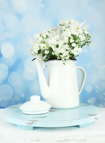 Beautiful chamomiles in teapot on table on bright background — Stock Photo, Image