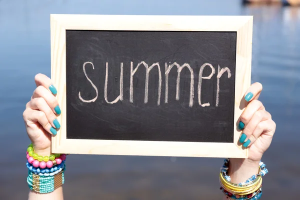 Chalkboard em branco na mão feminina no fundo da praia — Fotografia de Stock