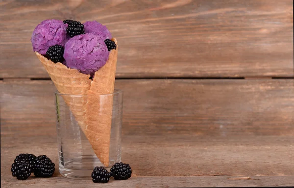 Gelato gustoso con bacche in cono di cialda su fondo di legno marrone — Foto Stock