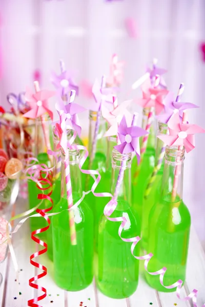 Botellas de bebida con paja y dulces sobre fondo decorativo — Foto de Stock