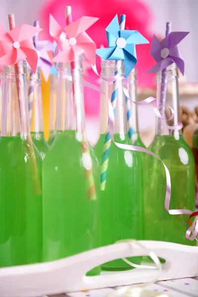 Drikkeflasker med halm på bordet på dekorativ bakgrunn – stockfoto