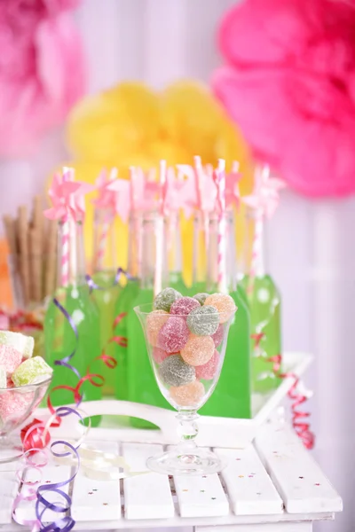 Garrafas de bebida com palha e doces em fundo decorativo — Fotografia de Stock