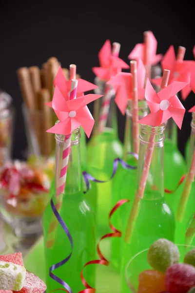 Botellas de bebida con paja y dulces sobre fondo oscuro — Foto de Stock