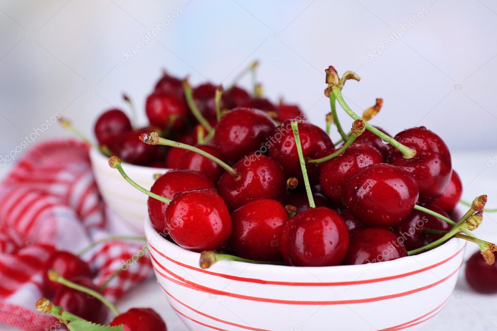 Ripe sweet cherries in bowl on wooden table