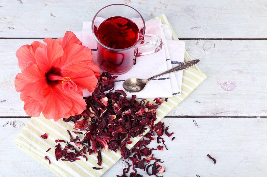 Hibiscus tea and flower on color napkin on wooden background