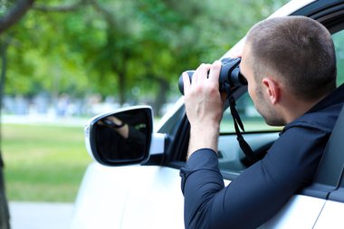 Man in car with binoculars clipart