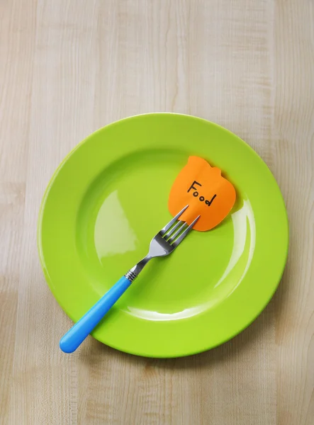Note paper with message  attached to fork, on plate, on color wooden background — Stock Photo, Image